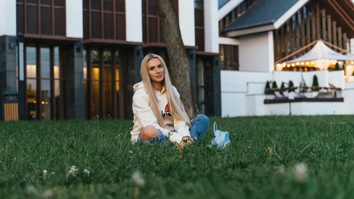 Casual outdoor portrait of a young woman seated on grass in a Minsk park during day.